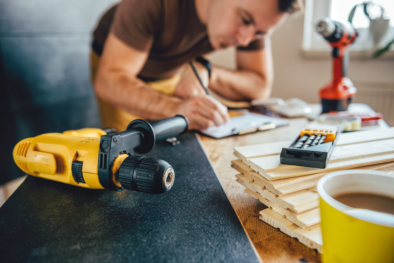 Homme qui écris sur une table remplis d'outils